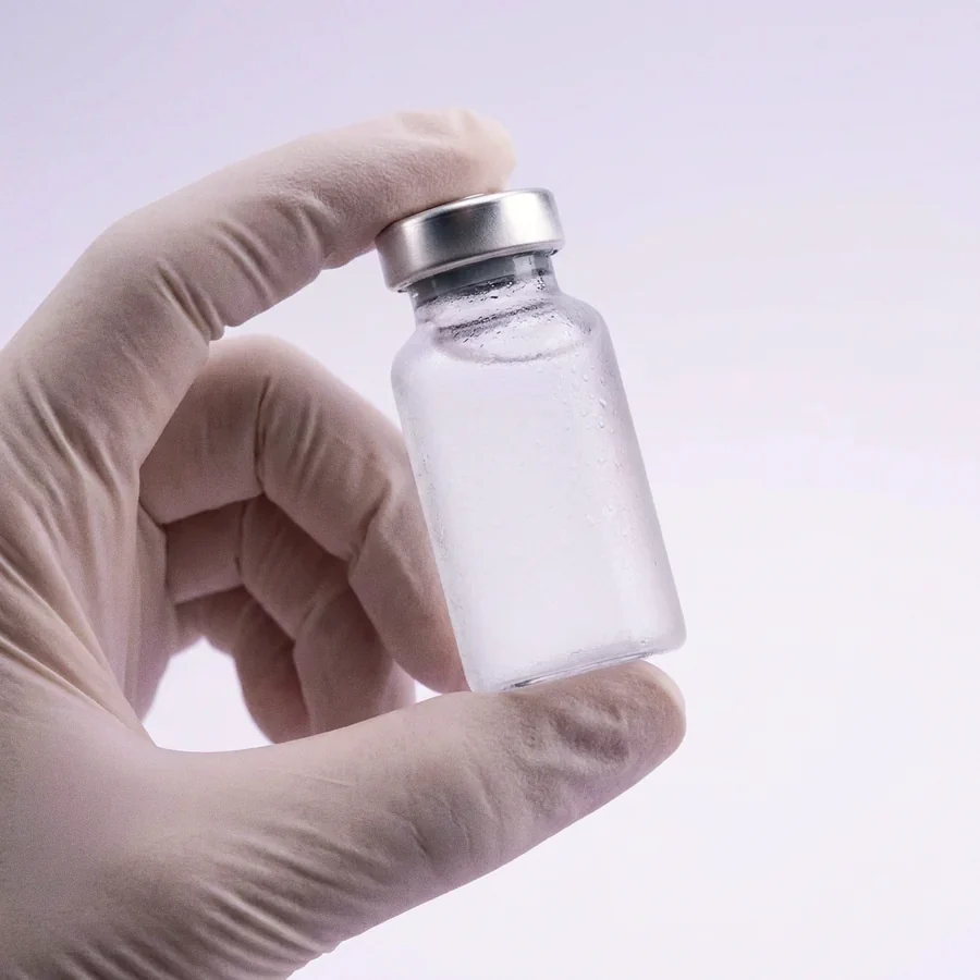 Gloved hand holding a compounded medication vial